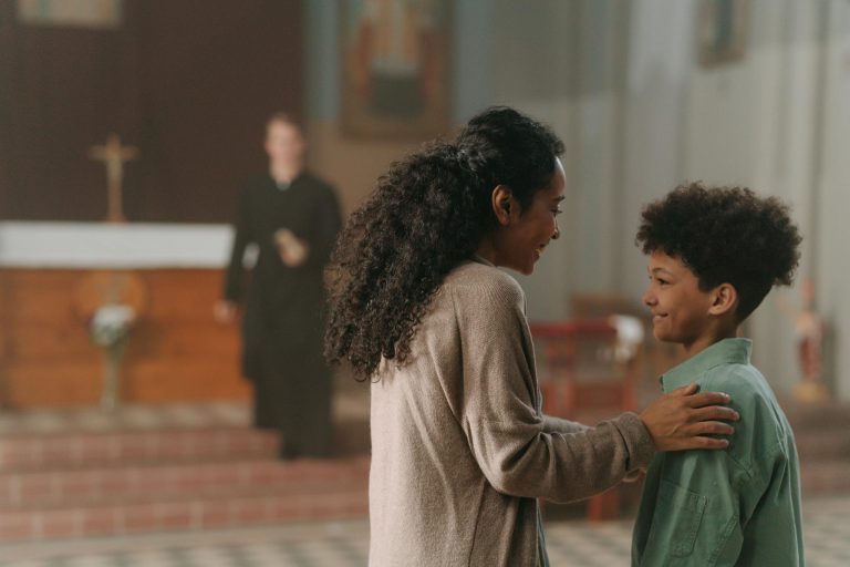 A mother and her son smiling at each other inside a church setting.
