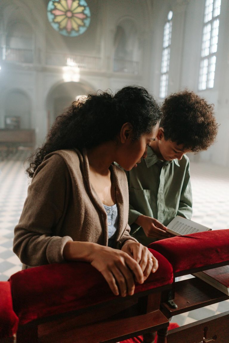 A mother and son peacefully pray inside a beautifully lit church, emphasizing faith and devotion.